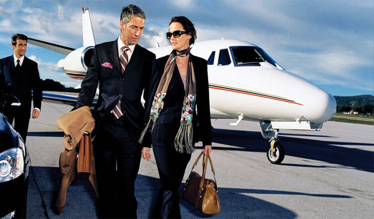 A man on a black suit and a woman on a black suit walking away on an airplane and approaching a car.