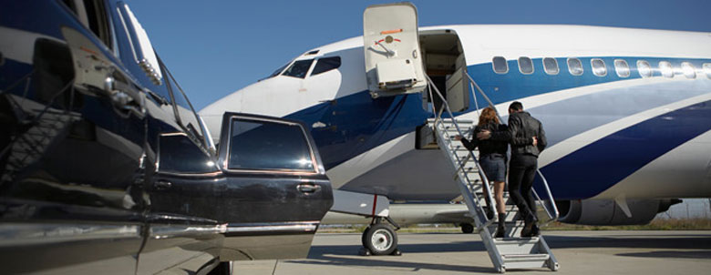 A limousine and an airplane, with a woman and man going inside.
